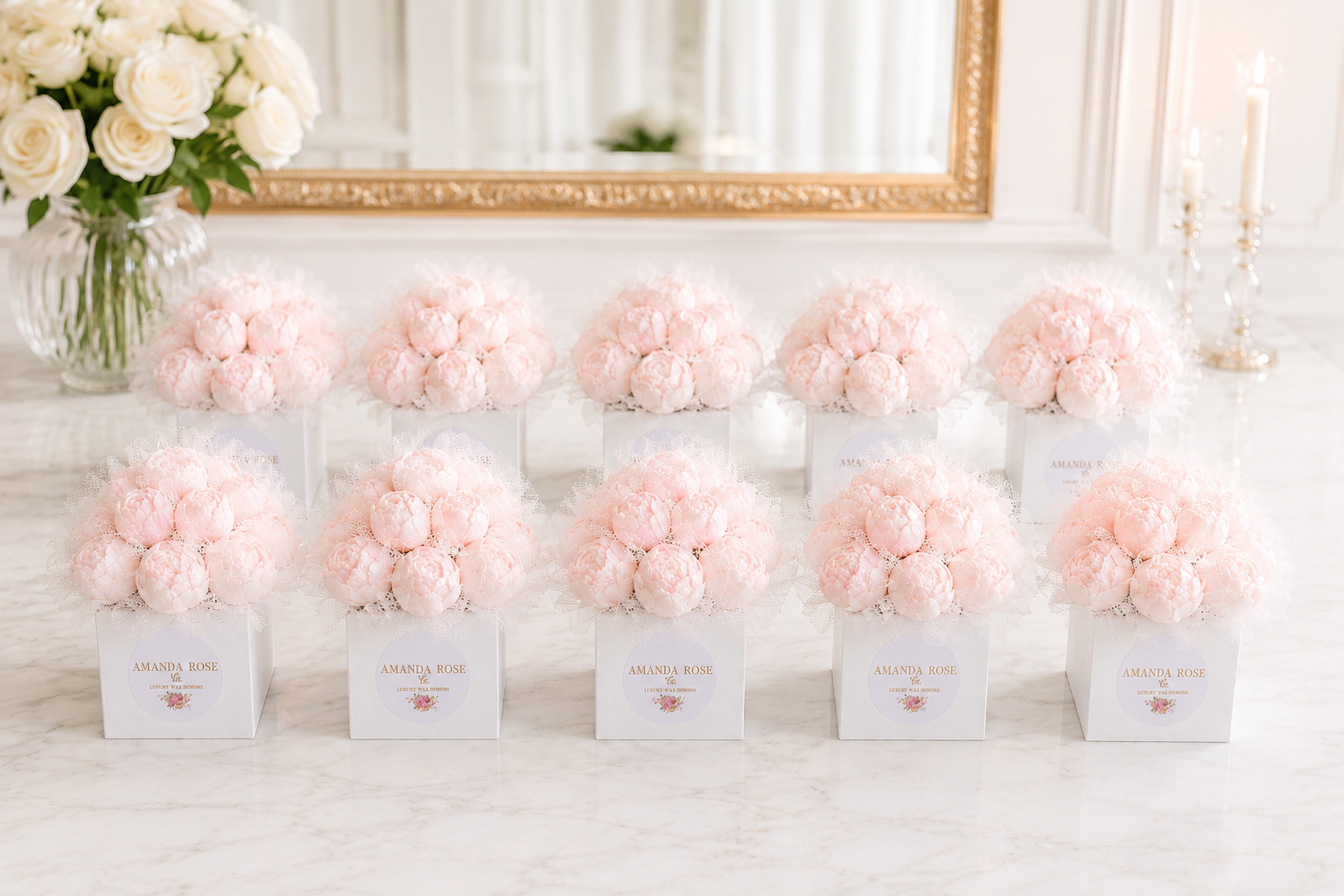 Bouquets of pink flowers in white boxes on a marble surface with a decorative mirror in the background.