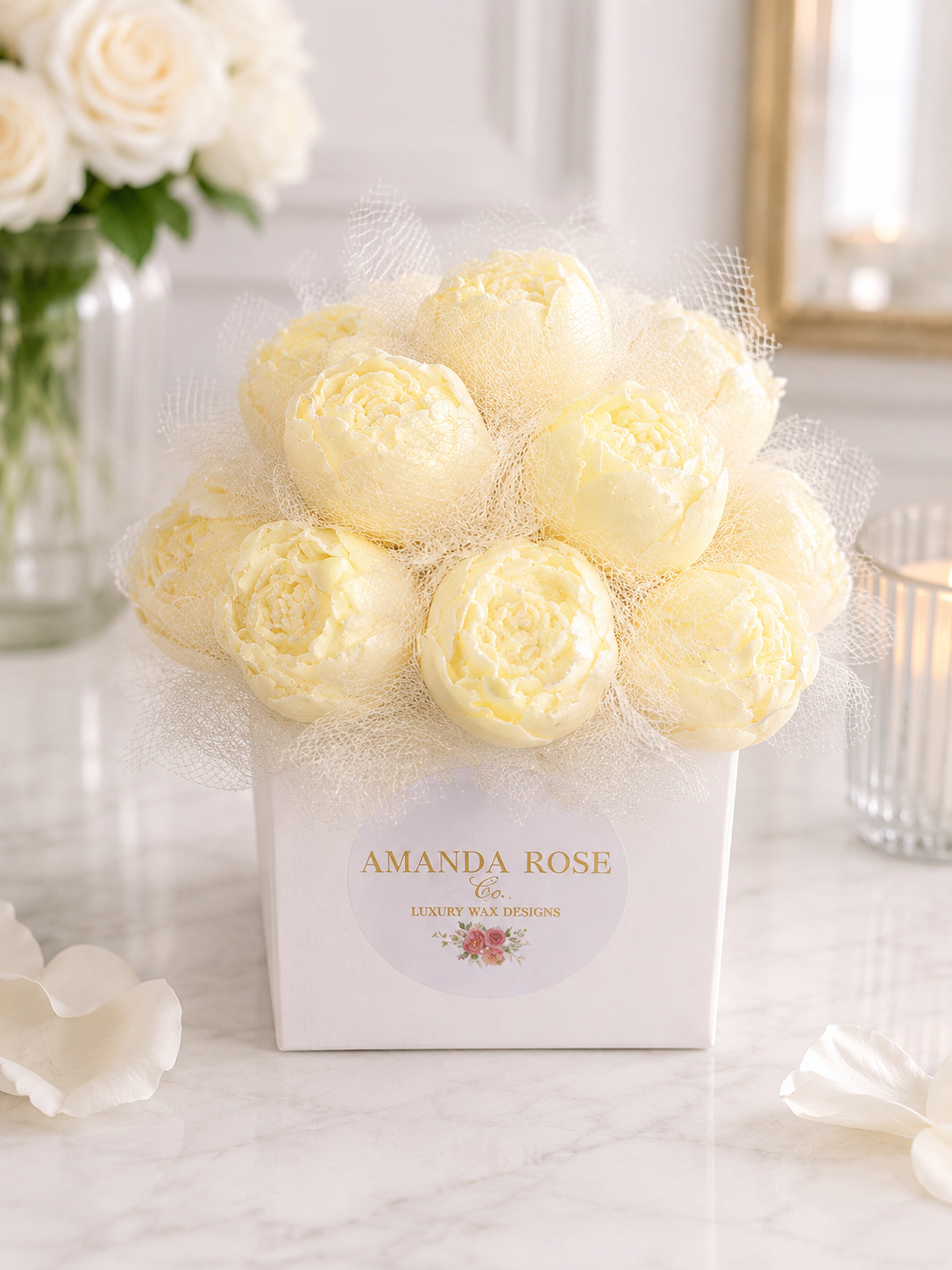 Bouquet of white roses in a box with 'Amanda Rose' branding on a marble surface.