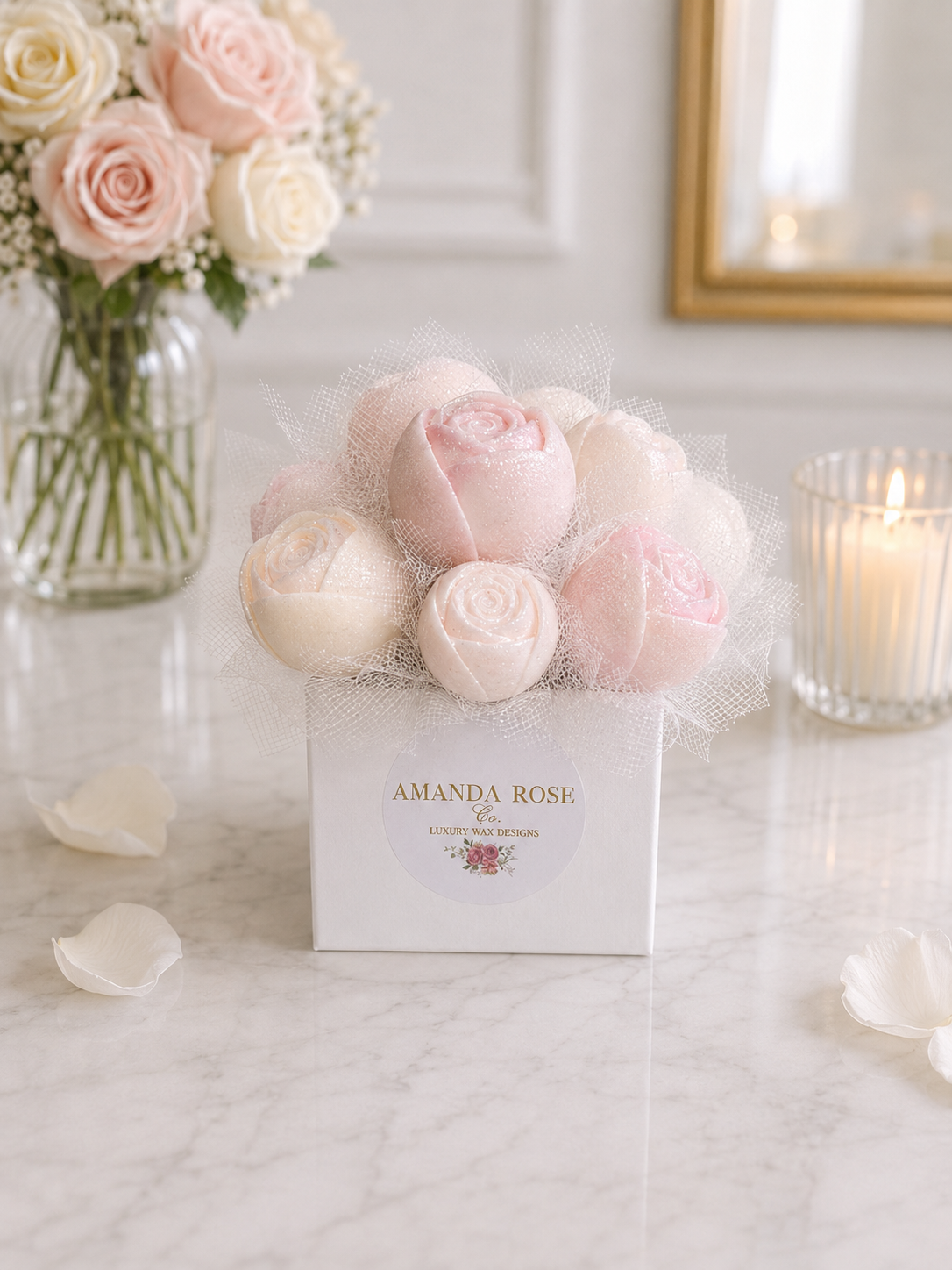 Bouquet of pink and white roses in a box with 'Amanda Rose' branding on a marble surface.