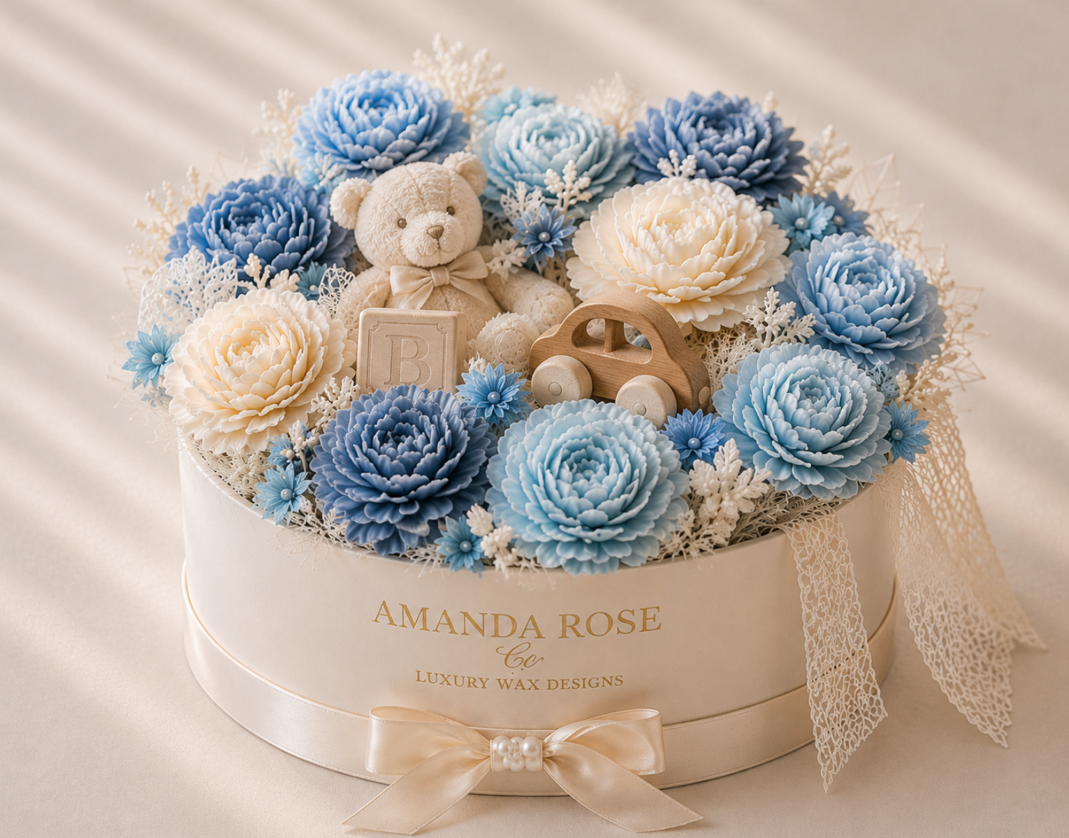 Decorative box with blue and white flowers, a teddy bear, and wooden car, branded 'Amanda Rose'.