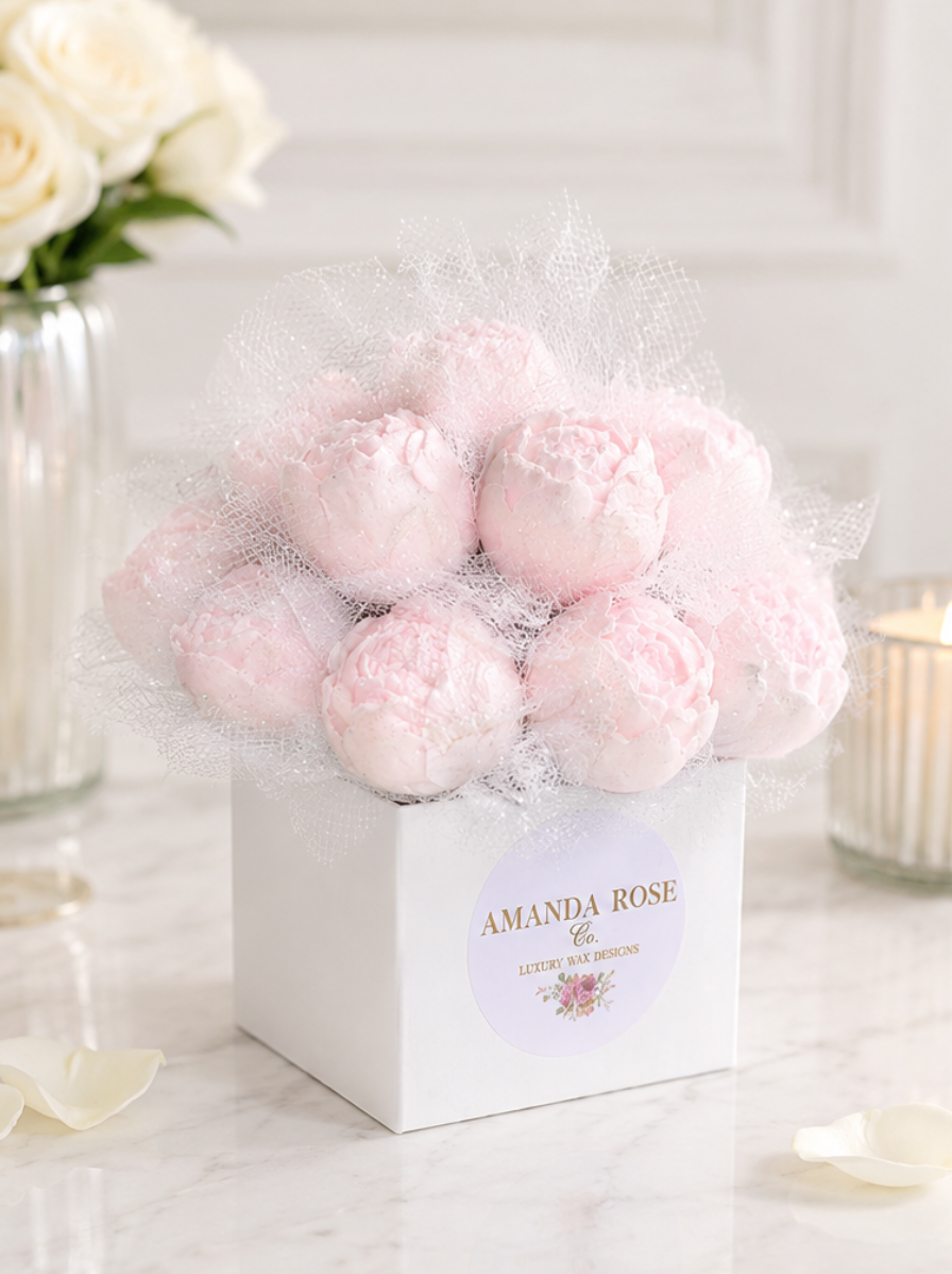 Pink peonies in a white box with 'Amanda Rose' label on a marble surface.